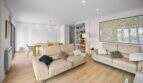Bright living room with leather sofa, dining table and parquet floor in house Felanitx