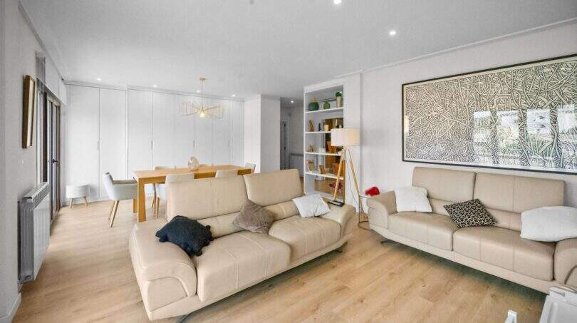 Bright living room with leather sofa, dining table and parquet floor in house Felanitx
