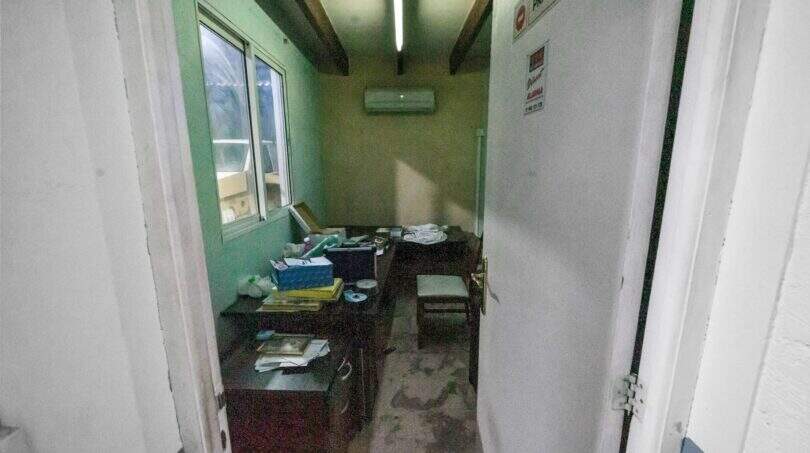 Small, untidy office room with green walls, wooden beams, air conditioning and desk in house Felanitx