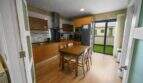 Spacious kitchen with wooden kitchen cabinets, dining table and access to terrace in house in Felanitx