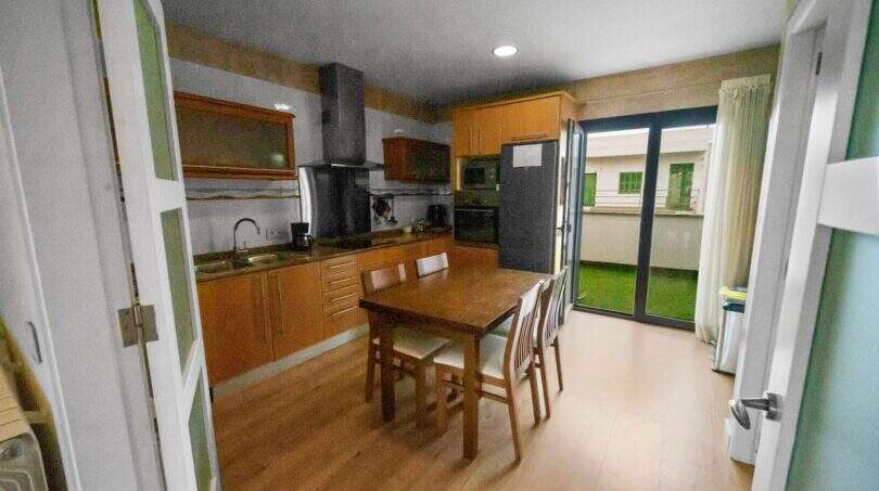 Spacious kitchen with wooden kitchen cabinets, dining table and access to terrace in house in Felanitx
