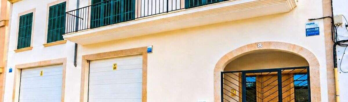 Exterior view of a white house in Felanitx with double garage, balcony and green shutters.