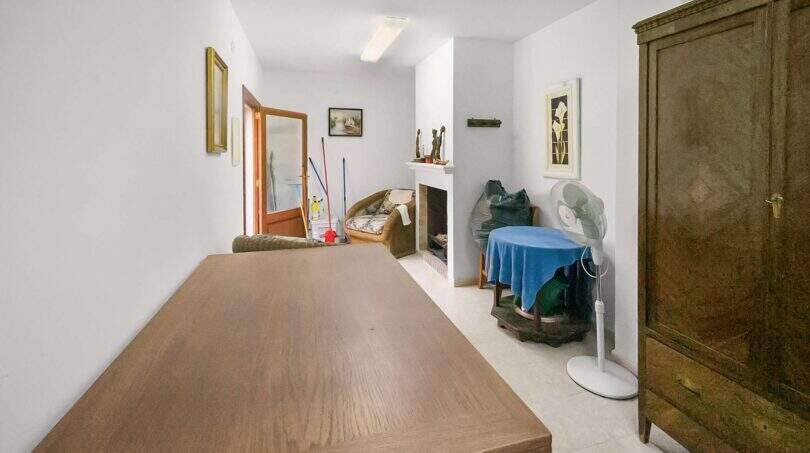 Living room with wooden table, fireplace, cupboard and fan in the charming 1900 townhouse in Felanitx