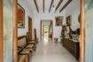 Entrance hall of the townhouse with wooden beam ceiling, rattan furniture, paintings and rustic wooden sculptures in Felanitx.