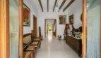 Entrance hall of the townhouse with wooden beam ceiling, rattan furniture, paintings and rustic wooden sculptures in Felanitx.