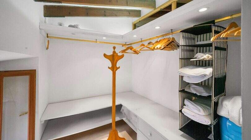 Spacious dressing room with gold clothing rail, wardrobe stand and fabric shelf with towels in the Felanitx townhouse