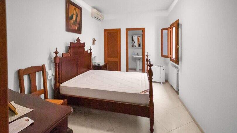 Bedroom with antique wooden bed, en-suite bathroom, air conditioning and radiator in the 1900 town house in Felanitx