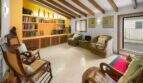 Living room with wooden beam ceiling, illuminated library and rattan furniture in the Felanitx townhouse