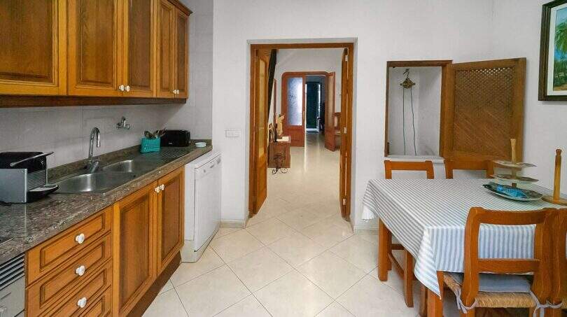 Kitchen with wooden cabinets, granite worktop and adjacent dining area in the historic townhouse in Felanitx