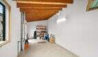Storage room with wooden beam ceiling, metal pipe, shelves and cardboard boxes in the 1900 townhouse in Felanitx.