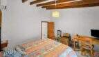 Bedroom with double bed, wooden beam ceiling, TV area and air conditioning in the Felanitx townhouse