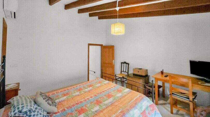 Bedroom with double bed, wooden beam ceiling, TV area and air conditioning in the Felanitx townhouse