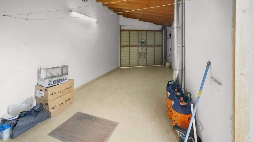 Spacious garage with wooden beam ceiling, tiled floors and roller door in the charming townhouse in Felanitx.