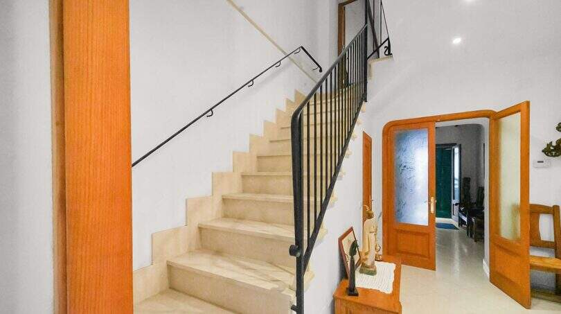 Bright staircase with marble steps, black iron railing and wooden doors in the historic townhouse in Felanitx.