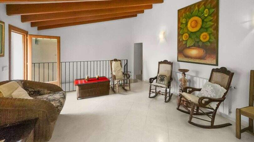 Living area in the Felanitx townhouse with wooden beam ceiling, rocking chairs and sunflower painting