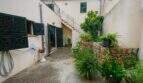 Courtyard of the historic townhouse in Felanitx with external staircase, green shutters and lush vegetation.