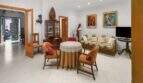 Living room with wooden furniture, display cabinet, sofa and art paintings in the charming 1900 town house in Felanitx.