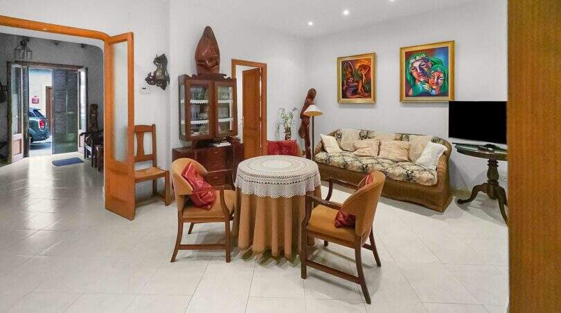 Living room with wooden furniture, display cabinet, sofa and art paintings in the charming 1900 town house in Felanitx.