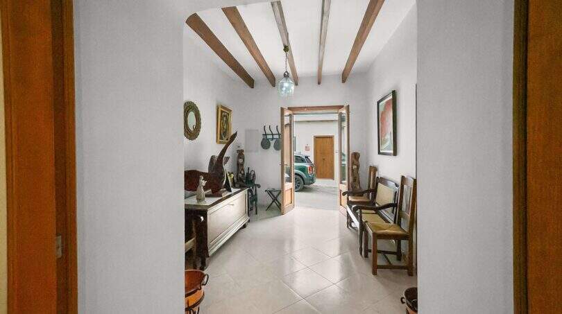 Bright entrance hallway with wooden beam ceiling, vintage decor and view of garage in town house Felanitx