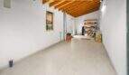 Spacious garage with wooden beam ceiling, shelf space and bright tiled floor in the Felanitx townhouse