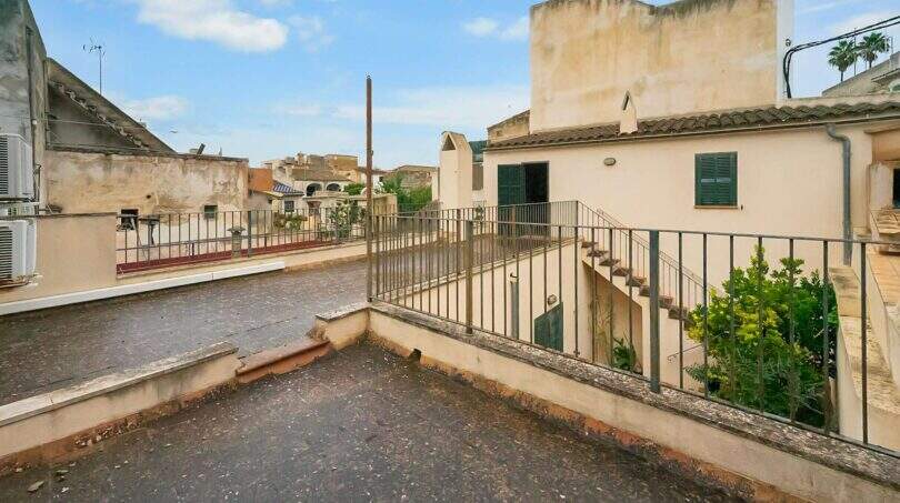 Roof terrace of the historic townhouse in Felanitx with metal railing, stairway and view of the old town.