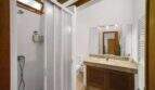 Bathroom with shower cubicle, marble washbasin, wooden base cabinet and towel heater in the Felanitx townhouse