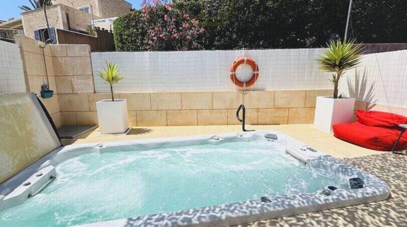 Außenbereich mit Whirlpool, Liegen und Palmen in Cala Llombards