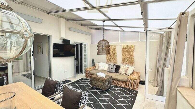 Überdachte Terrasse mit Rattansofa, Glasschiebedach und Bohème-Deko im Haus in Cala Llombards
