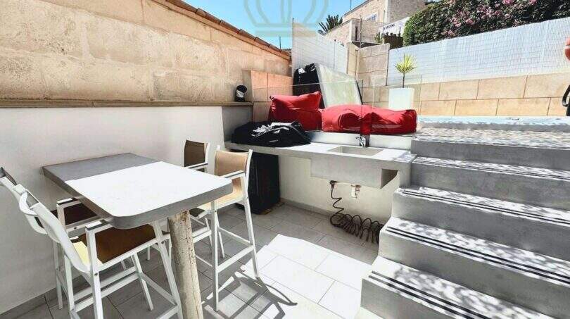 Überdachte Terrasse mit weißen Stühlen, Außenküche und Treppe zum Pool in Cala Llombards