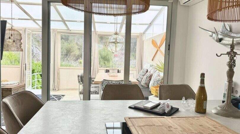 Helles Esszimmer mit Wintergarten, Rattanleuchten und Blick in den Garten, Haus in Cala Llombards