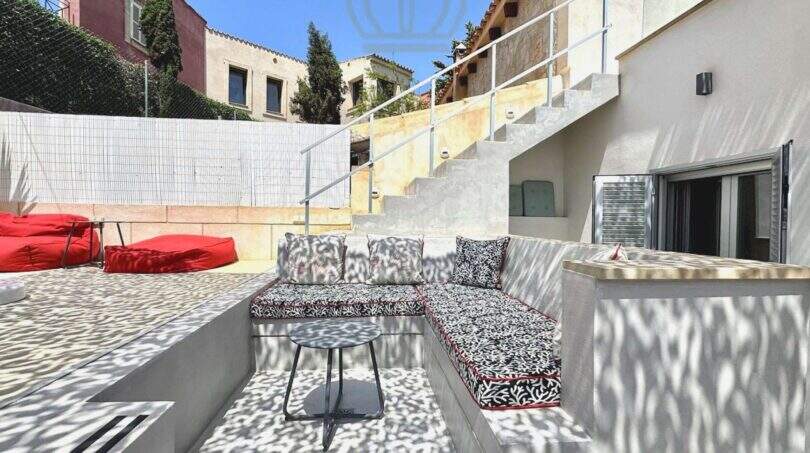 Mediterrane Terrasse mit gemustertem Ecksofa, roten Sitzsäcken und Treppenaufgang in Cala Llombards