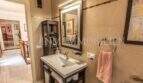 Modernes Badezimmer der Villa in Marratxí mit elegantem Waschtisch, beleuchtetem Spiegel und Beige-Fliesen.