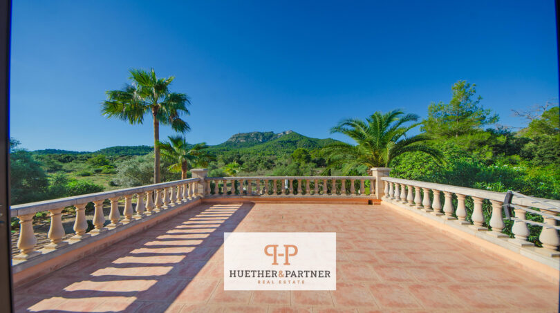 Amplia terraza en la azotea de la finca Felanitx con balaustrada, palmeras y vistas a Sant Salvador