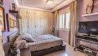 Schlafzimmer der Villa in Marratxí mit Doppelbett, Einbauschrank, TV und lilafarbenen Wänden.