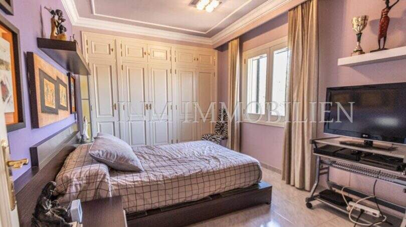 Schlafzimmer der Villa in Marratxí mit Doppelbett, Einbauschrank, TV und lilafarbenen Wänden.