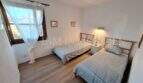 Helles Schlafzimmer mit zwei Einzelbetten, Holzboden und Fenster zur Gartenansicht in Wohnung Port de Sóller