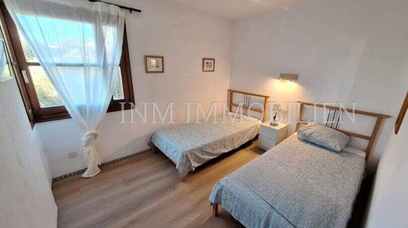 Helles Schlafzimmer mit zwei Einzelbetten, Holzboden und Fenster zur Gartenansicht in Wohnung Port de Sóller