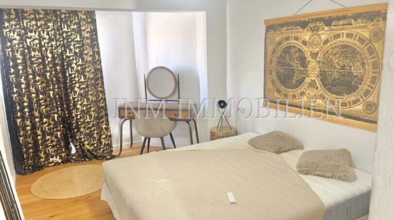 Helles Schlafzimmer mit Doppelbett, Holzboden, Weltkarte-Wandbild und elegantem Vorhang in renovierter Wohnung Palma
