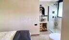 Modernes Schlafzimmer mit Deckenventilator und offenem Badbereich mit Regendusche und freistehender Badewanne