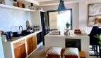 Moderne Küche mit Kochinsel, Holzakzenten und Pendelleuchte im Penthouse an der Playa de Palma