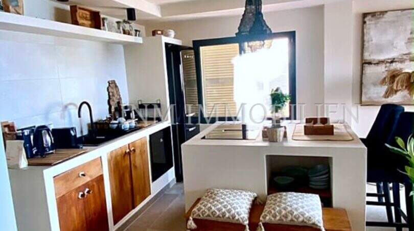 Moderne Küche mit Kochinsel, Holzakzenten und Pendelleuchte im Penthouse an der Playa de Palma