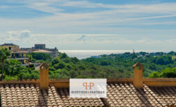 Rooftop terrace of a Mallorca apartment with tile roof, sea view and lush Mediterranean vegetation