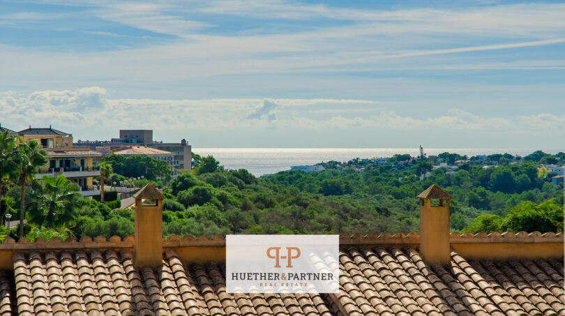 Dachterrasse einer Mallorca-Wohnung mit Ziegeldach, Meerblick und üppiger mediterraner Vegetation