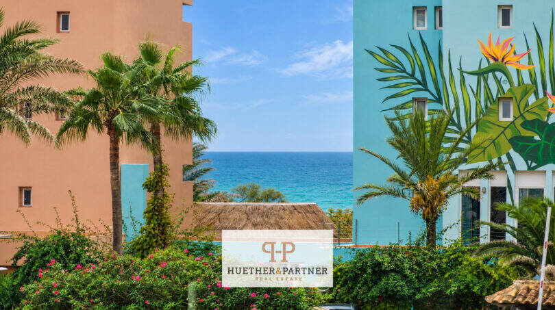 Außenansicht Penthouse Colonia de Sant Jordi, bunte Fassaden mit Wandmural, Palmen und Meerblick unter blauem Himmel