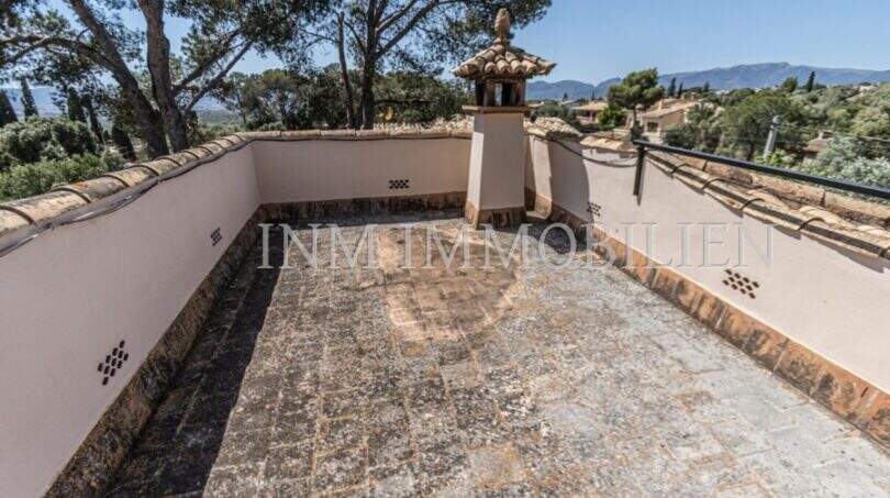 Dachterrasse der Villa in Marratxí mit Natursteinboden, Schornstein und Bergpanorama im Hintergrund.