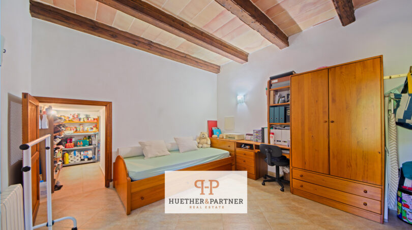 Schlafzimmer der Finca Felanitx mit Holzbalkendecke, Einzelbett, Schreibtisch und Einbauschrank
