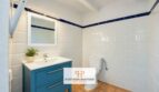 Baño luminoso de la finca en Felanitx con lavamanos azul, azulejos blancos y patrón de cenefa azul.