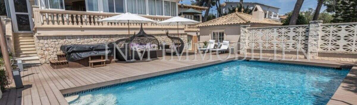 Villa in Marratxí: Außenbereich mit blauem Pool, Holzterrasse, Sonnenliegen und mediterraner Fassade mit Pinien.