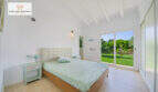 Helles Schlafzimmer mit Doppelbett, Holzboden und Glasschiebetür zum gepflegten Garten in Sa Ràpita.