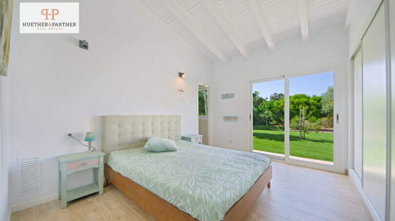 Helles Schlafzimmer mit Doppelbett, Holzboden und Glasschiebetür zum gepflegten Garten in Sa Ràpita.